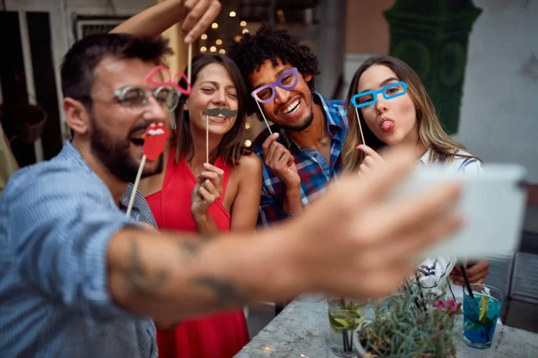 A group of friends having fun at a party, putting on masks and taking selfies as a keepsake.